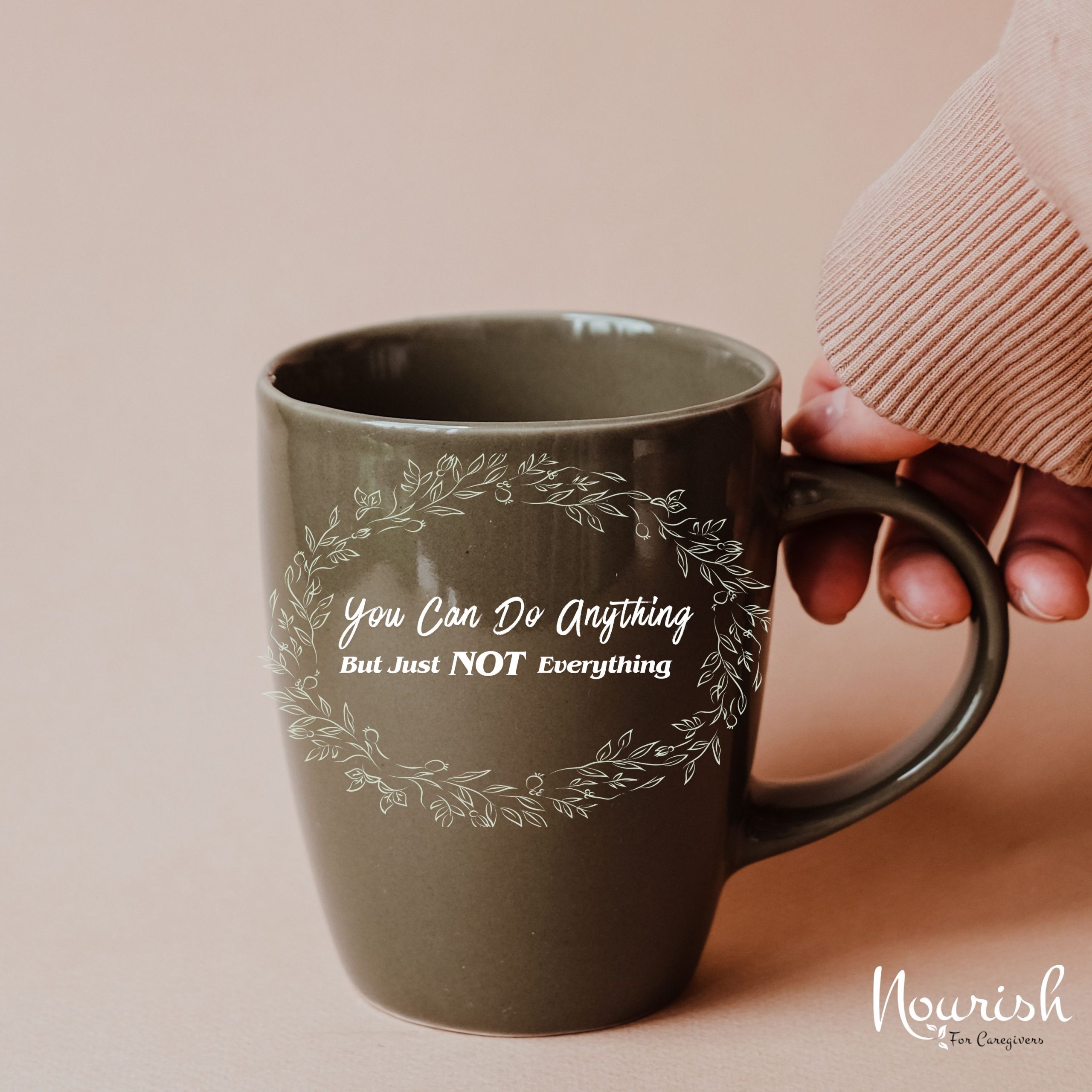 A hand holds a green mug with white text that reads, You can do anything but just NOT everything, surrounded by a leafy wreath design. The bottom corner shows the Nourish for Caregivers logo and highlights support from Family Caregiver Resources.